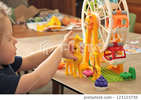 Child plays with a plastic constructor at home on table. Children and educational games. Animals of Africa and an amusement park. Child plays with a plastic constructor at home on table. Children and educational games. Animals of Africa and an amusement park. 123123730