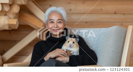 Happy smiling elderly woman holding hamster in cozy wooden setting 123124301