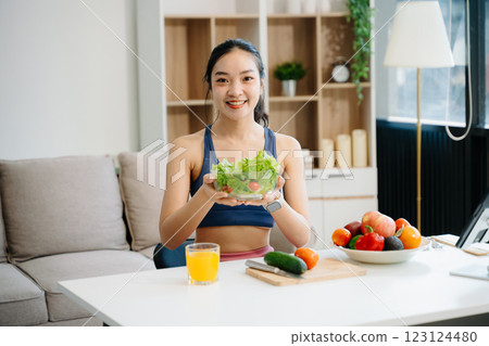 Woman enjoys a fresh salad with fruits and juice, embodying wellness, nutrition, and vitality 123124480