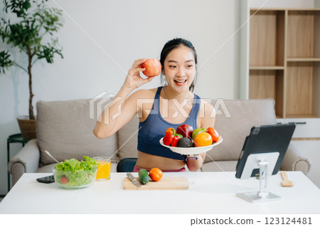 Woman enjoys a fresh salad with fruits and juice, embodying wellness, nutrition, and vitality 123124481