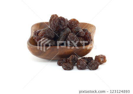 Small wooden bowl brimming with plump, dark raisins, ready to be enjoyed as snack or used in baking. 123124893