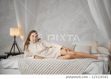 Cozy indoor setting with a woman relaxing on a bed in soft light Cozy indoor setting with a woman relaxing on a bed in soft light 123128161