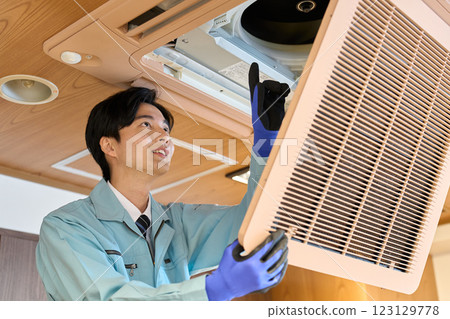 A man checking the air conditioning equipment in a restaurant 123129778