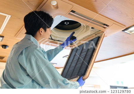 A man checking the air conditioning equipment in a restaurant 123129780