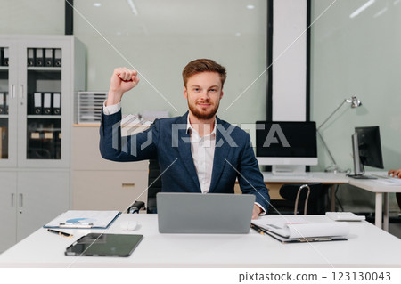 Excited Young Businessman Celebrating Success in Modern Office. 123130043