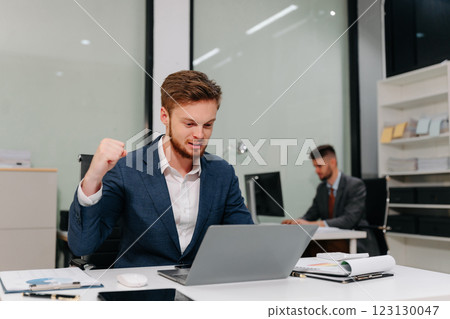 Excited Young Businessman Celebrating Success in Modern Office. 123130047