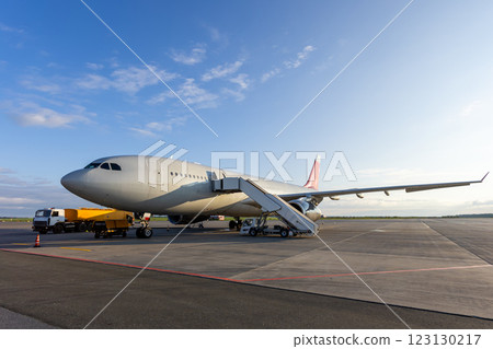 Wide body passenger jetliner with aircraft steps at the airport. Airfield tanker refueling an airplane Wide body passenger jetliner with aircraft steps at the airport. Airfield tanker refueling an airplane 123130217