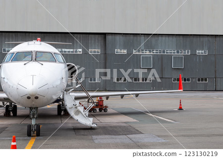 Front view of the executive airplane with an opened gangway door at the airport near aircraft hangar Front view of the executive airplane with an opened gangway door at the airport near aircraft hangar 123130219