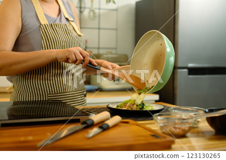 Cropped shot of a woman carefully serving her meal on wooden kitchen counter Cropped shot of a woman carefully serving her meal on wooden kitchen counter 123130265