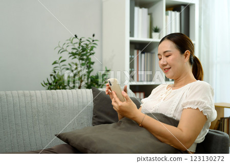 Middle aged woman relaxing on the sofa and using smartphone in a living room Middle aged woman relaxing on the sofa and using smartphone in a living room 123130272