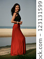 Portrait of a beautiful woman 51 years old posing in a red silk skirt and Indian earrings on the ocean shore Goa India 123131599