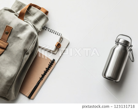 A minimalist flat lay of a canvas backpack, spiral notebook, pen, and stainless steel water bottle A minimalist flat lay of a canvas backpack, spiral notebook, pen, and stainless steel water bottle 123131718