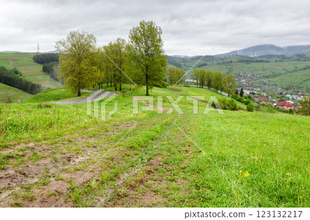 countryside scenery of ukraine in spring. cloudy weather. carpathian mountain landscape with grassy hills and meadows, forested slopes and town in the valley. volovets district countryside scenery of ukraine in spring. cloudy weather. carpathian mountain landscape with grassy hills and meadows, forested slopes and town in the valley. volovets district 123132217