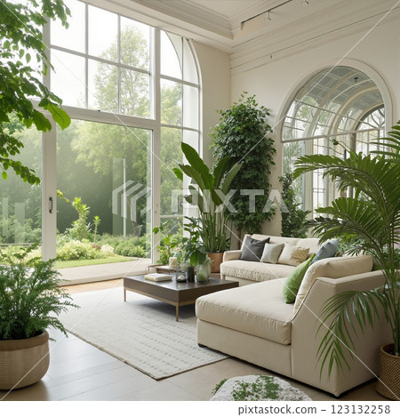 A bright, modern living room with large windows, lush greenery 123132258