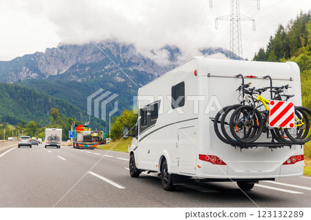 Scenic view big modern white family rv camper van vehicle drive Europe highway road alpine mountain cloud in summer day. Rving motorhome lifestyle travel and adventure tourism trip journey concept 123132289