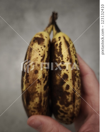 Two overripe bananas showing brown spots held by a hand Two overripe bananas showing brown spots held by a hand 123132410