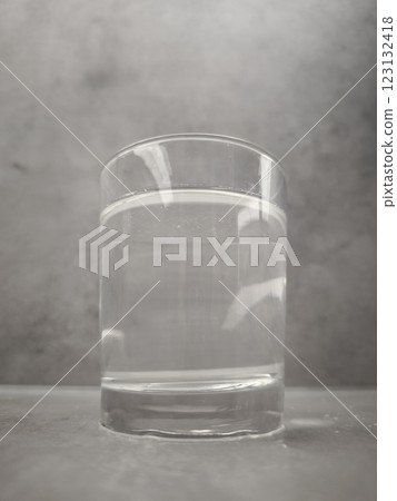Clear glass of still water sits on a gray surface, reflecting the light in prague, czechia World Water Day copy space 123132418