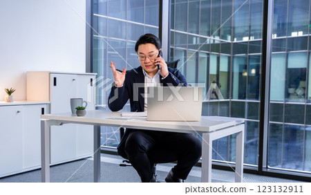 Professional Businessman Talking on Phone With Laptop in Modern Office 123132911