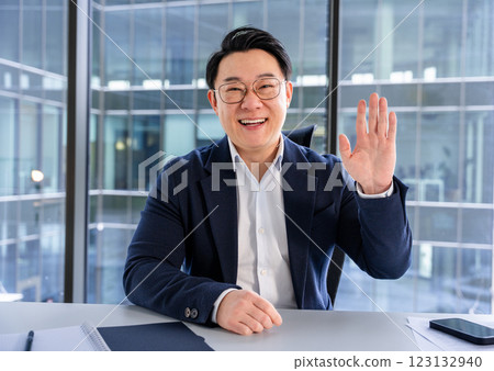 Professional Businessman Waving and Smiling in Modern Office Workspace Professional Businessman Waving and Smiling in Modern Office Workspace 123132940