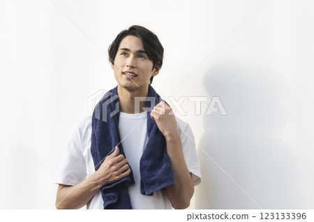 A man in his 20s with a towel draped over his shoulders A man in his 20s with a towel draped over his shoulders 123133396