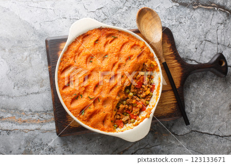 Sweet potato shepherd's pie with ground turkey, green peas, onions, peppers and tomatoes close-up in a baking dish. Horizontal top view 123133671