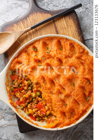 Healthy shepherd's pie made with ground meat, vegetables and topped with a layer of fluffy mashed sweet potatoes closeup on the baking dish. Vertical top view 123133676