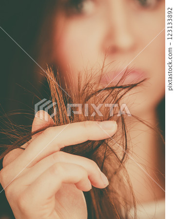 Worried woman looking at her dry hair ends 123133892