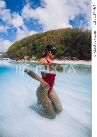 Woman in a red swimsuit and mask swims and posing in tropical waters, split shot Woman in a red swimsuit and mask swims and posing in tropical waters, split shot 123134464