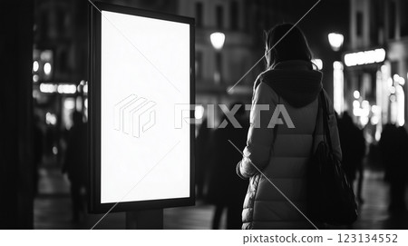 Woman stands looking at white empty shining advertising billboard on city street at night Woman stands looking at white empty shining advertising billboard on city street at night 123134552