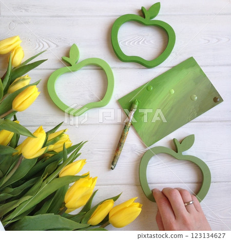Yellow tulips, green apple-shaped frames on white wooden background Yellow tulips, green apple-shaped frames on white wooden background 123134627