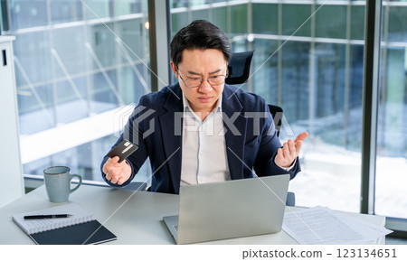 Frustrated Businessman Using Laptop at Office with Credit Card in Hand 123134651