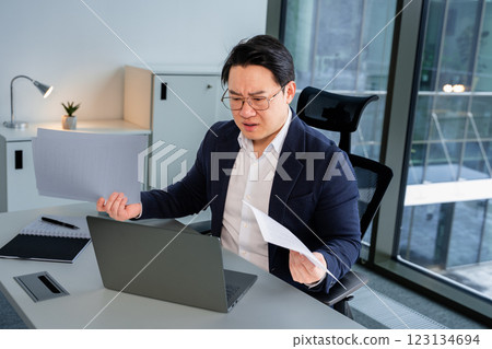 Professional Businessman Reviewing Documents in a Modern Office Setting Professional Businessman Reviewing Documents in a Modern Office Setting 123134694