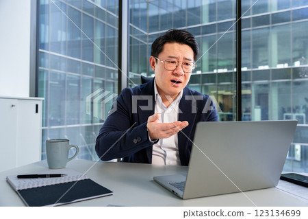 Confused Businessman Gesturing While Working on Laptop in Modern Office 123134699