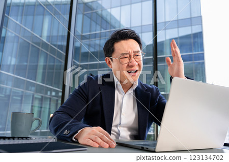 Frustrated Businessman Reacting to a Computer Issue in Modern Office Setting Frustrated Businessman Reacting to a Computer Issue in Modern Office Setting 123134702