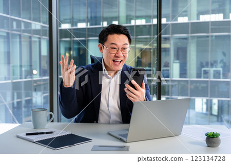 Excited Businessman Using Smartphone in Modern Office With Bright Window View 123134728