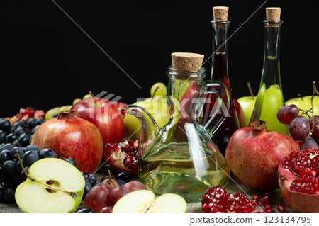 Vinegars in glass vinegar bowls on black background among fruits. 123134795