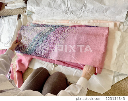 A woman's hands folding a pink furisode kimono on a folding paper 123134843