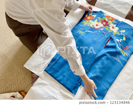 A woman's hands spreading out a blue furisode kimono on a wrapping paper 123134846