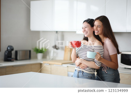 Funny interracial lesbian couple drinking and looking away 123134999