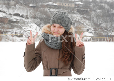 Winter portrait of a smiling girl in a cozy outfit with snowy background Winter portrait of a smiling girl in a cozy outfit with snowy background 123135005