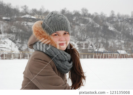 Winter portrait of a smiling woman in warm clothing outdoors in snowy landscape 123135008