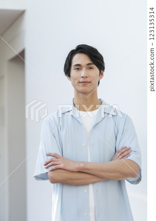 A man in his 20s looking at the camera with his arms crossed 123135314