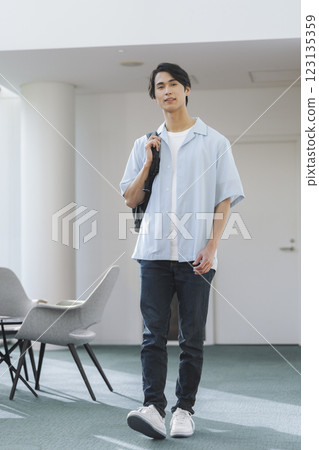 一名 20 多歲的男子，肩上背著背包，看著鏡頭，肖像 123135359