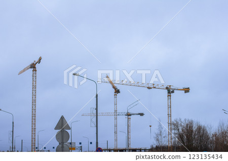 Towering construction cranes dominate the skyline, busily working on a large-scale building project, symbolizing growth, development, and progress in urban environment. Towering construction cranes dominate the skyline, busily working on a large-scale building project, symbolizing growth, development, and progress in urban environment. 123135434