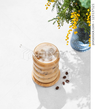 Cold coffee latte or mocha in a glass with milk and ice on a light background with a bouquet  123137121