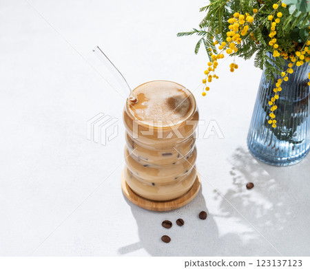 Cold coffee latte or mocha in a glass with milk and ice on a light background with a bouquet Cold coffee latte or mocha in a glass with milk and ice on a light background with a bouquet 123137123