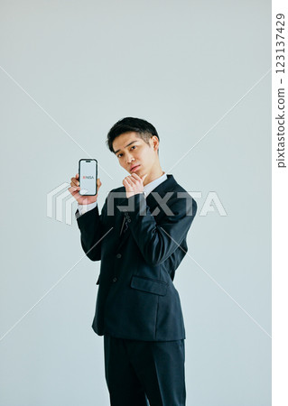 一名 20 多歲的年輕男子手持智慧型手機 新 NISA 123137429