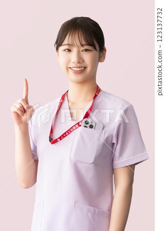 A female medical staff member pointing with her index finger up 123137732
