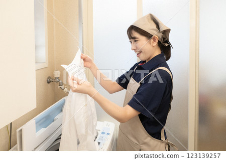 拿著洗過的T恤的微笑的女人 拿著洗過的T恤的微笑的女人 123139257
