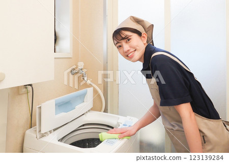 A female housecleaning worker wiping a washing machine 123139284